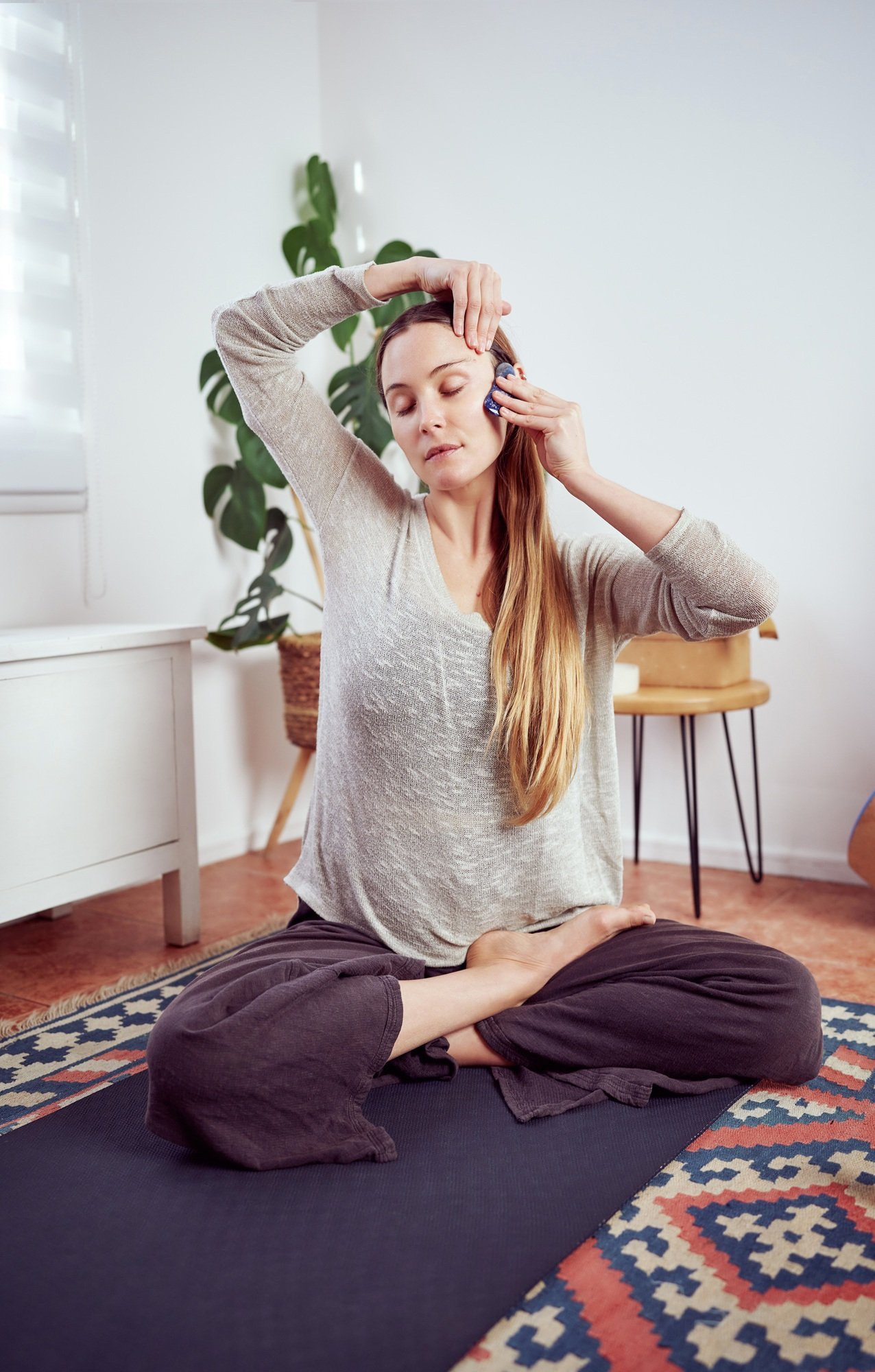 woman massaging her temples and face with manual quartz massager, facial yoga and anti aging